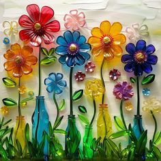 there are many colorful flowers in vases on the glass wall behind them is grass