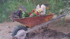 a wheelbarrow filled with flowers in the dirt