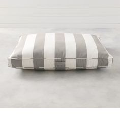 a green and white striped pillow sitting on top of a gray floor next to a wall