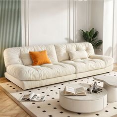 a white couch sitting on top of a rug in a living room next to a table