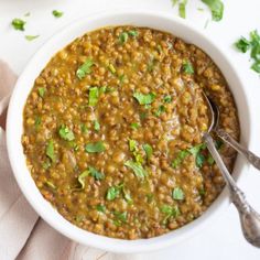 a white bowl filled with lentils and topped with cilantro