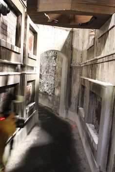 a person riding a skateboard down a narrow alley in an old building with graffiti on the walls