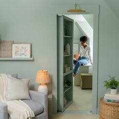 a woman sitting on top of a book shelf in a living room