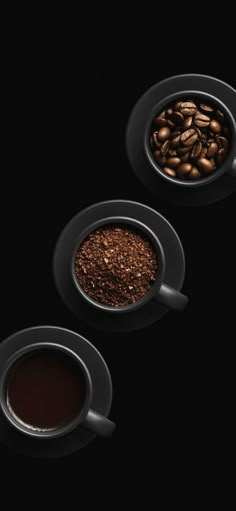 three coffee cups filled with different types of coffee beans and ground coffee on black background