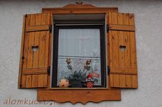 a window with wooden shutters on the side of a building that has plants in it