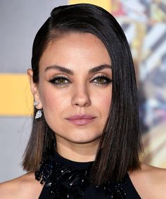 a close up of a person with dark hair and smoky eyeshadow, wearing a black dress