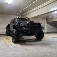 a large black truck parked in a parking garage with yellow lights on it's roof