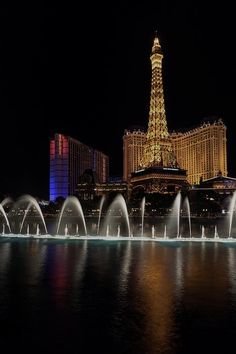 the eiffel tower is lit up at night in front of the las vegas strip