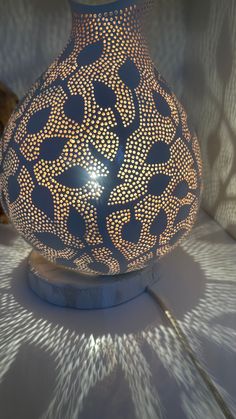 a blue vase sitting on top of a table next to a lamp shade with an intricate design