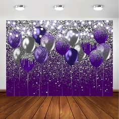 purple and silver balloons are hanging in front of a wall that has glittery confetti on it