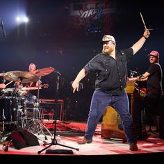 a man standing on top of a stage holding a drumstick in front of him