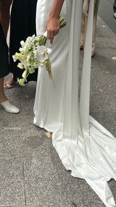 the bride and groom are standing on the sidewalk with their wedding bouquets in hand