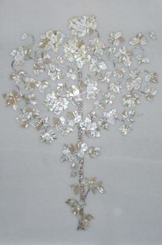 a tree made out of crystal stones on a white surface with leaves and flowers attached to it