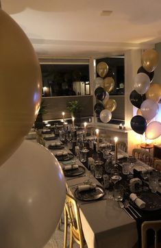 a dining room table set for a party with balloons, candles and plates on it