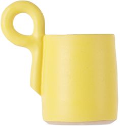 a yellow cup with a pair of scissors sticking out of it's side on a white background