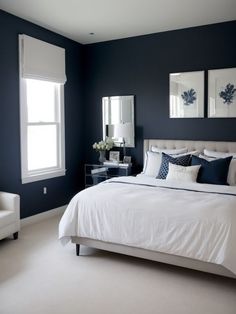 a bedroom with blue walls, white bedding and two framed pictures on the wall