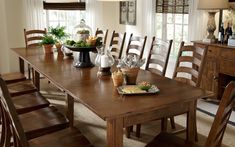 a dining room table and chairs in front of windows