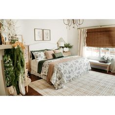 a bed room with a neatly made bed and a christmas tree on the side of the bed