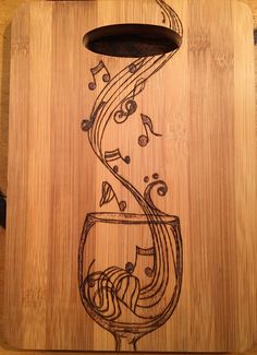 a wooden cutting board with music notes and a glass of wine on the bottom side