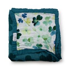 a green and white blanket with shamrocks on it's side, folded up in front of a white background