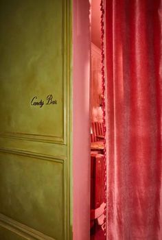 a red curtain with the name candy bar written on it is in front of a green door