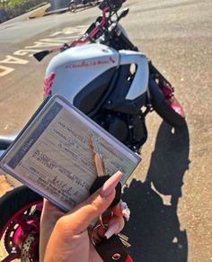 a person holding up a parking ticket in front of a parked motorbike on the street