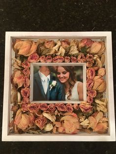 a photo frame with flowers and a couple in the middle is on a black surface