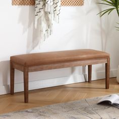 a wooden bench sitting on top of a hard wood floor next to a potted plant