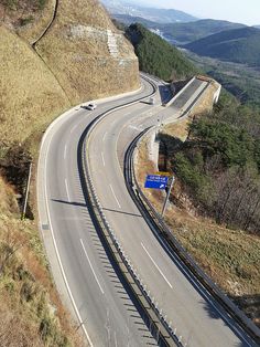 an aerial view of a curved road in the mountains