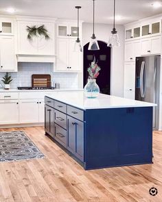 a kitchen with white cabinets and blue island