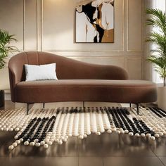 a brown couch sitting on top of a wooden floor next to a potted plant