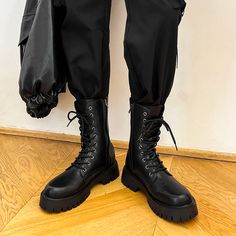 a person in black pants and boots standing on the floor