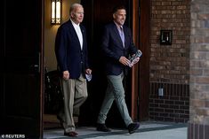 two men in suits walking out of a building