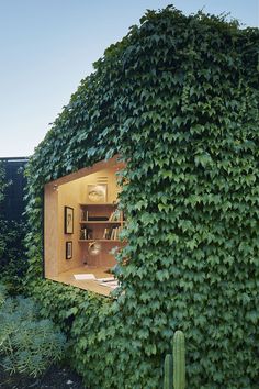 a house covered in green plants with an open door