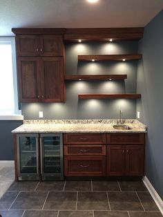 an empty kitchen with dark wood cabinets and marble counter tops