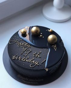 a black and gold birthday cake on a white countertop with the words happy birthday written in gold