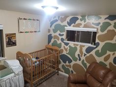 a baby's room with camouflage wallpaper and leather furniture