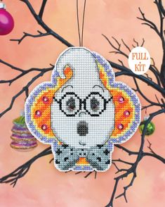 a cross stitch ornament with a dog wearing glasses and a fireball hanging from it's back