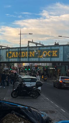 a busy city street filled with lots of traffic next to a tall blue and yellow sign