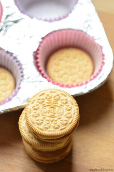 four cookies sitting on top of each other in tin foil trays next to an empty container