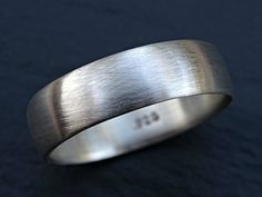 a close up of a wedding ring on a black surface with the word bg engraved in it