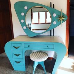 a blue vanity with a mirror and stool