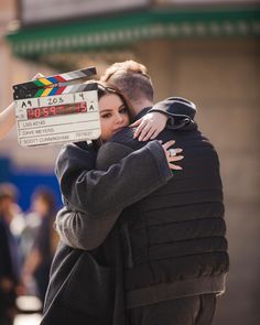 a man and woman hugging each other while holding a clapper in front of them