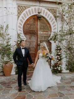 a bride and groom holding hands in front of a door