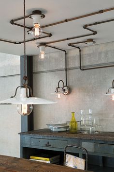 an industrial style light fixture hangs from the ceiling above a table with glasses and bottles on it