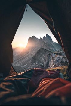 the view from inside a tent looking at mountains and valleys in the distance with sunlight coming through