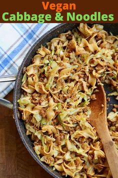 a skillet filled with cabbage and meat on top of a wooden table next to a blue checkered napkin