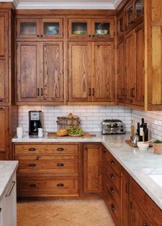 a kitchen with wooden cabinets and marble counter tops, along with white tile backsplash