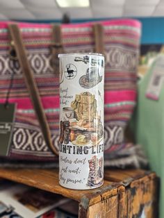 a can sitting on top of a wooden table next to a handbag and purse