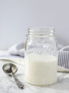 a glass jar filled with milk next to a spoon